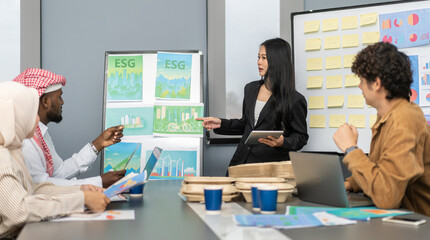 Diverse team professionals collaborating on sustainable development project during a corporate meeting, presentation eco-friendly designs with charts and data on renewable energy and green technology
