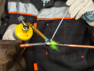 worker soldering copper pipes with a gas torch
