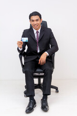 Young Asian businessman with club card sitting on office chair