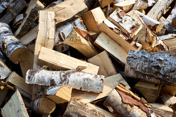 Stack of birch firewood with hand chopping block. Chopped firewood for winter. Lot of firewood - harvesting wood for heating the house. Horizontal photo. Chopped firewood background and texture.