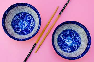 A blue floral ceramic bowl and two wooden chopsticks.