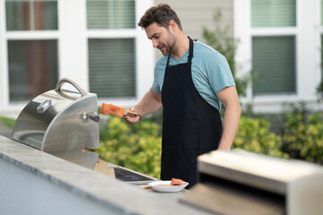 a male chef in an apron grills salmon steak with vegetables for dinner. A chef grilling fish on an open flame, preparing it with herbs and lemon. man cooking salmon on grill outdoor grill salmon fish