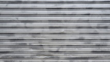 Metallic grey rolling door with striped front pattern.  Old white zinc wall texture or old metal texture background. Roll up door texture. garage door stripped texture.