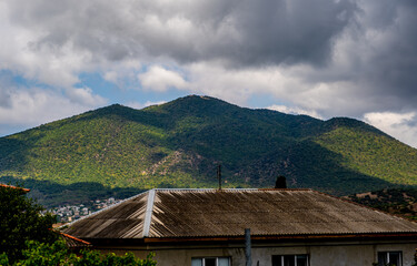 An old house under a slate on the background of a mountain.