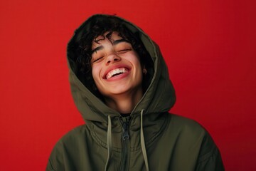 Smiling person in green hoodie against vibrant red background