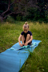 a little 5-year-old girl in a black minimalist jumpsuit does gymnastics in the garden, outdoors