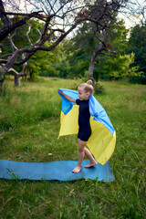 a little 5-year-old gymnast in a black minimalist jumpsuit is practicing with the flag of Ukraine...