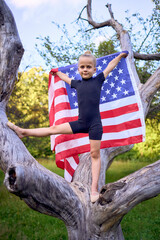     a   little 5-year-old gymnast in a black minimalist jumpsuit is practicing with the flag of...
