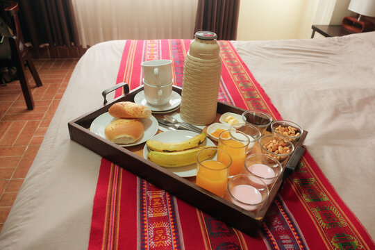 Breakfast in bed room service. closeup of wooden tray on bed, on colourful runner with traditional weave pattern. Healthy wholesome meal provided by hotel hostel stay or guesthouse in Uyuni, Bolivia