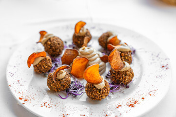 Falafel als Vorspeise auf einem Teller schön angerichtet mit Süßkartoffel Chips und Hummus