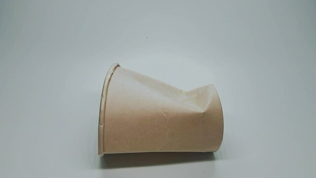 Crumpled paper drink cup on stop motion video isolated on white background. Environment friendly concept.	