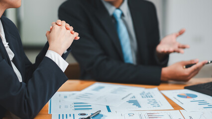 Professionals in a business meeting analyzing financial reports and charts, discussing data and strategies in a modern office environment.