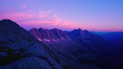 Flat lay of a mountain top view at dusk, with the sky turning shades of pink and purple as the last light of day fades behind the peaks.