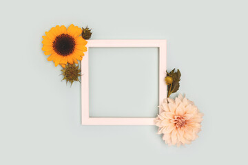 Square frame made of sunflowers and dahlia flowers on a blue background. Place for your design.