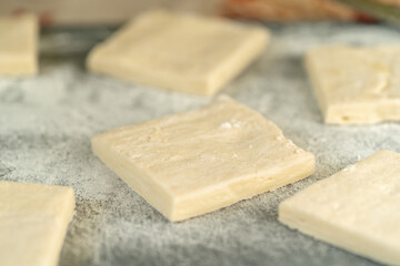 Raw puff pastry cut into squares for making cookies on the kitchen table closeup