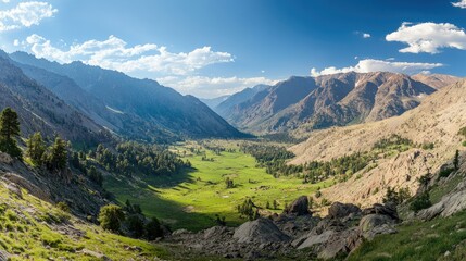 Naklejka premium Top view of a green valley surrounded by towering mountain peaks, with ample sky above for copy space, ideal for outdoor adventure promotions.