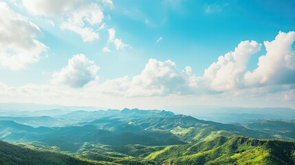 Top view of a lush green mountain range, with a large expanse of blue sky for copy space, ideal for outdoor adventure or nature advertisements.