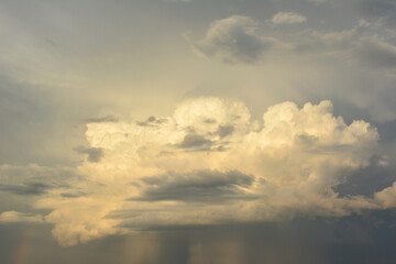 a thundercloud isolated on the gray and dark blue sky with a rainbow