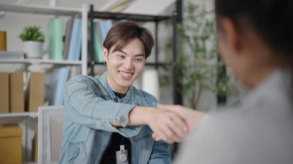 Young creative Asian business professionals in smart casual shake hands with big smiles after interview in a modern office environment. greeting collaborative spirit and dedication concept