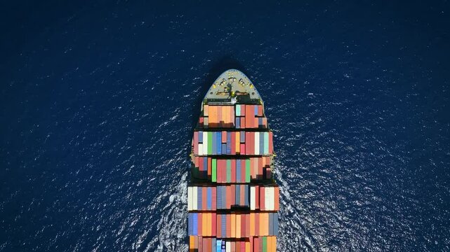 Aerial overhead tracking of an  industrial container cargo ship crossing the sea with speed