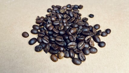 whole roasted coffee beans scattered on beige background. side view. for making an invigorating drink