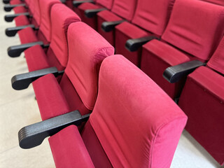 A close-up view of rows of chairs upholstered in red velvet.