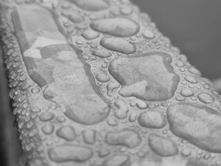 Water drops on a metal surface close view, raindrops on a fence black and white monochrome grayscale photo