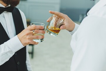 A man's hand in a classic suit with a glass of whiskey. Drinks for men.