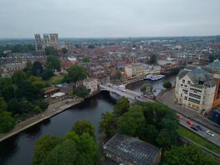 Obraz premium Lendal Tower and Lendal bridge in York, UK. High altitude aerial towards Cathedral at dusk before rain. River Ouse waterfront with restaurant and river cruise boats mooring.