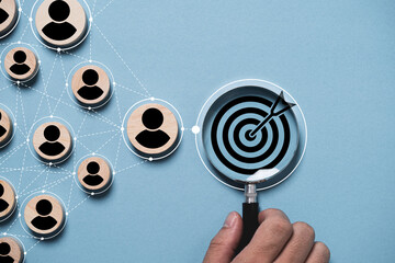 Dartboard and black arrow inside magnifier glass with connection linkage between human icon for customer focus target group and customer relation management concept.