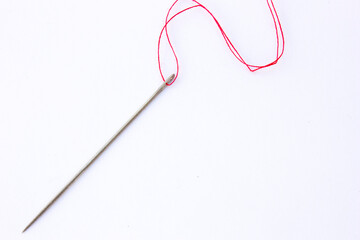This clean and simple image showcases a sewing needle placed on a white background. The needle is positioned in the center of the frame.