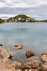 Rocky beach and hill with St Nicholas church in Tribunj, Croatia