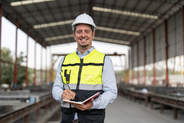 Portrait of male civil engineer wearing safety vest with white helmet standing and working at...