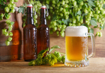 mugs of beer, green hops, bottles and beer barrel
