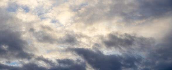 the sky is covered with thick clouds illuminated by the evening sun