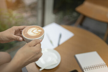 Women holding a coffee in the coffee shop. Selective focus and blurred background.