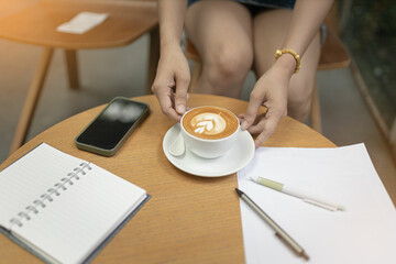 Women holding a coffee in the coffee shop. Selective focus and blurred background.