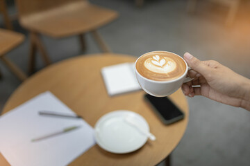 Women holding a coffee in the coffee shop. Selective focus and blurred background.