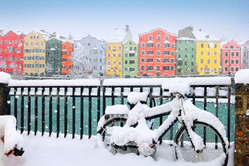 Beautiful winter cityscape. Snowy weather, colorful city houses, fence, bright teal water of Inn...