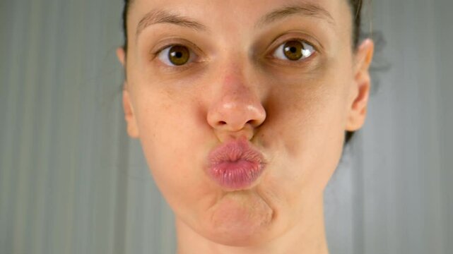 Woman engaging in facial yoga exercises to enhance beauty health of skin. Brunette woman puffs out her cheeks and purses her lips. Face beauty techniques for muscle strengthening. Skincare wellness.