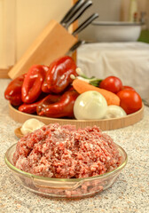 Raw minced meat in front of peeled vegetables for cooking.