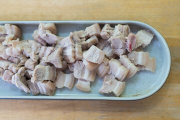 Slices of boiled pork belly bite sized pieces in long tray