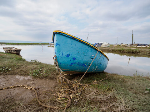 Blue boat is tied to a muddy dock. Heswall, Dee estuary.