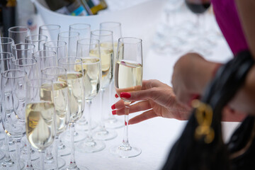 Close-up view of woman hand taking drinking glass  with champagne from buffet table on party or...