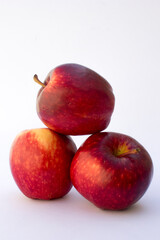 Three Red Apples in the white background. Apples also provide copper to produce red blood cells, vitamin A to maintain healthy organ functioning, vitamin E to reduce inflammation.