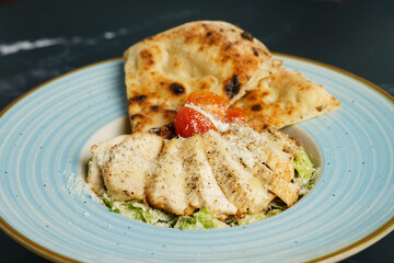Caesar salad with fried chicken slices, tomato, parmesan cheese, tomato and crispy focaccia