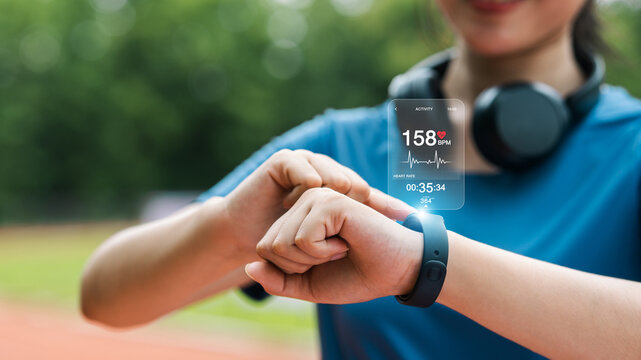 Young woman checking her wristwatch via app to measure her heart rate. Healthy exercise concept. Running, walking.