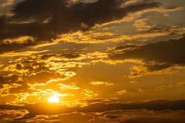 the evening sky illuminated by the sun hidden behind a cloud. evening sky with clouds and sun. the...