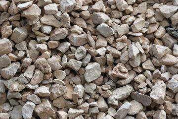 Close up of numerous small, irregularly shaped stones with varying shades of brown and beige. Stones are densely packed, creating a textured surface that could be interesting for its natural patterns