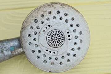 one old gray part from a shower head made of metal and plastic lies on a yellow wooden table